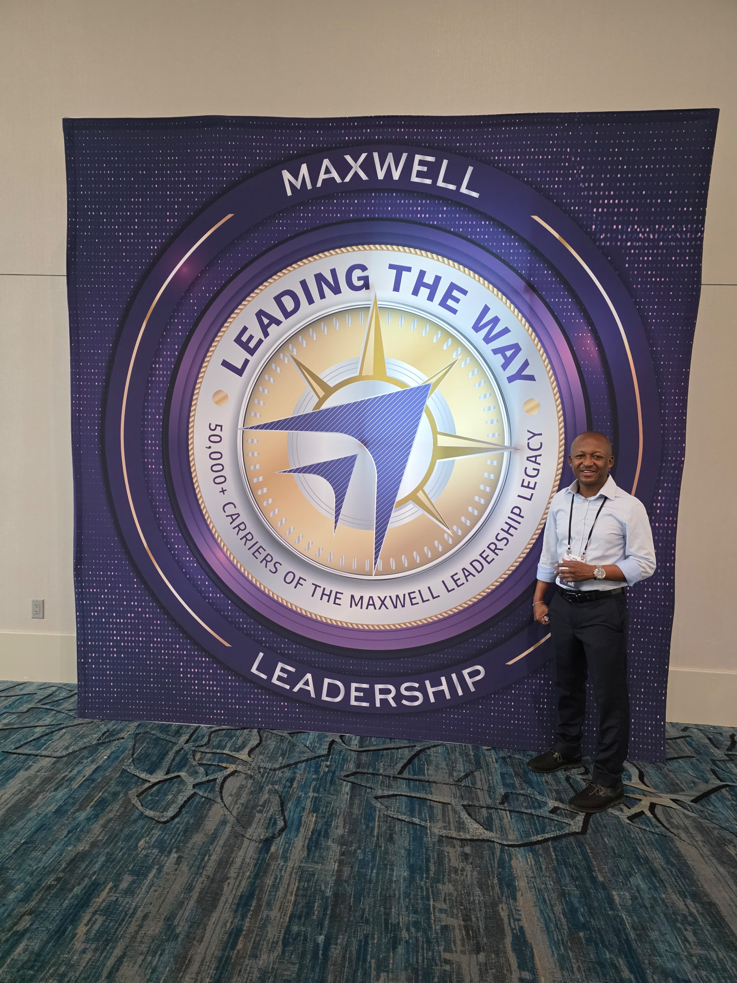 Nene standing beside the Maxwell Leadership 'Leading the Way' backdrop